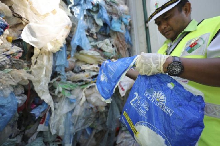 Empleados del Ministerio de Medio Ambiente examinan un contenedor lleno de plástico no reciclable (AP Foto/Vincent Thian).