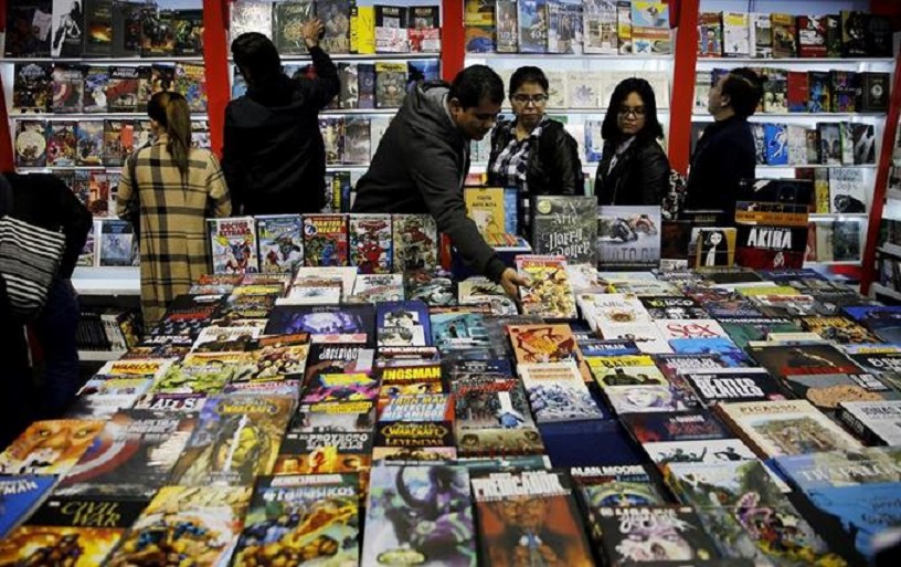 Hombre revisa ejemplares ofrecidos en Feria del libro.