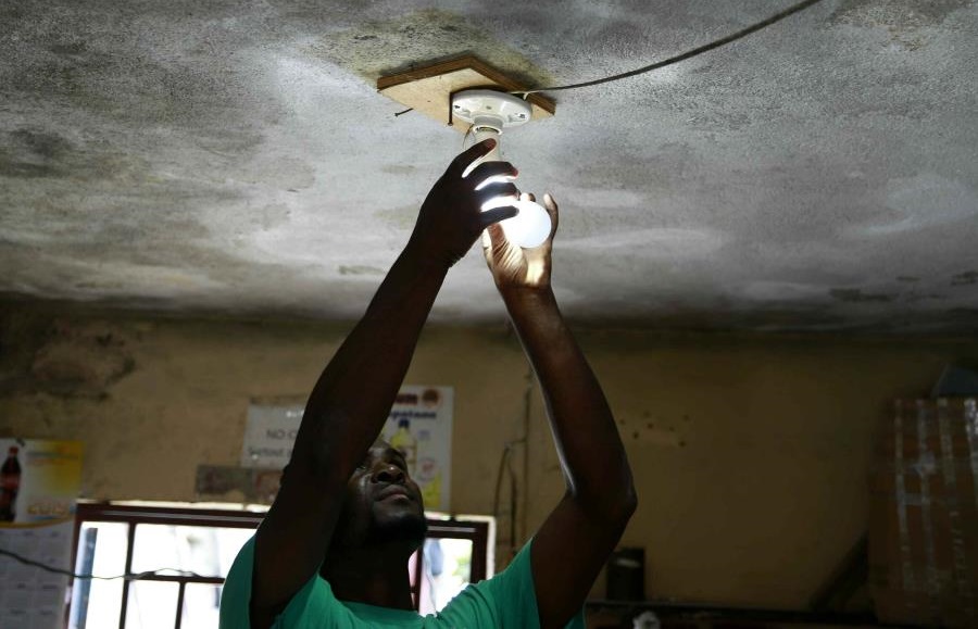 Hombre enciende bombilla en su casa en Haití.