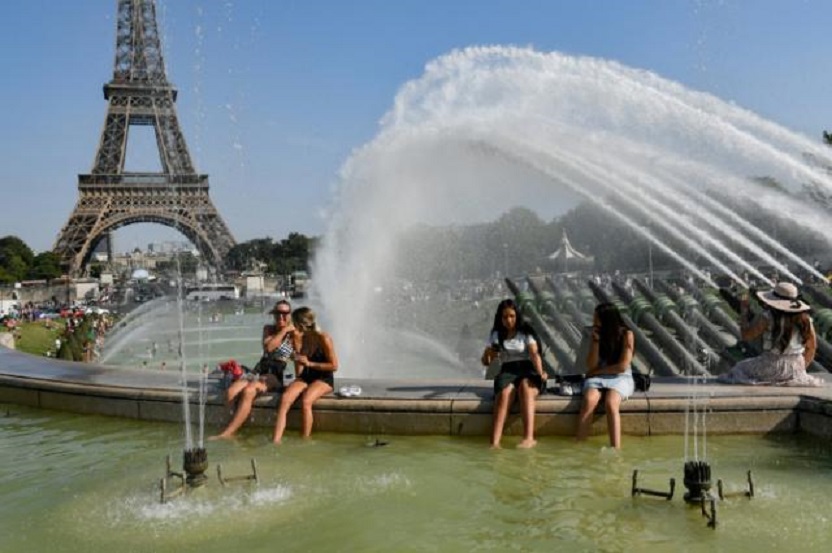 La gente combate la ola de calor refrescándose en las fuentes de Trocadero, detrás la Torre Eiffel en París.