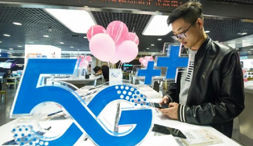 Un cliente mira un teléfono móvil junto a un logotipo de tecnología 5G en una tienda en Hangzhou, China.