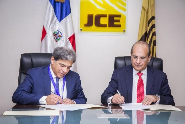 Presidente de la JCE, Julio César Castaños Guzmán, y el director general y representante legal de la empresa auditora, Jaime Guevara, firman acuerdo.(Foto externa)