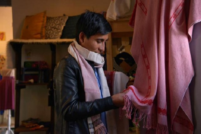 Alberto López, un tejedor y diseñador de modas indígena mexicano que hace prendas tradicionales, revisa un poncho en su tienda en San Cristóbal de las Casas.