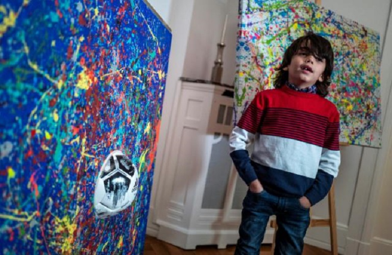 Artista alemán de 7 años Mikail Akar posa delante de sus obras.