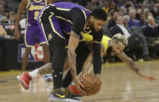 El jugador de los Warriors de Golden State Ky Bowman toca un balón de Anthony Davis, de los Lakers de Los Ángeles, en la primera mitad del juego de la NBA que enfrentó a ambos equipos, en San Francisco, el 27 de febrero de 2020. (Foto: AP/JEFF CHIU)