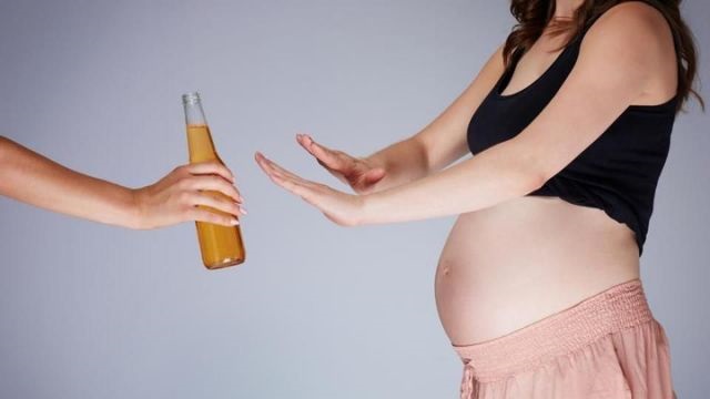 Imagen ilustrativa de una mujer embarazada rechazando una botella presumiblemente con alcohol. (Foto: Shutterstock)
