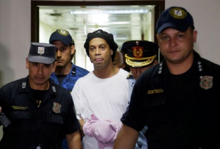 El exfutbolista brasileño Ronaldinho avanza esposado en la Corte Suprema de Paraguay, en Asunción.