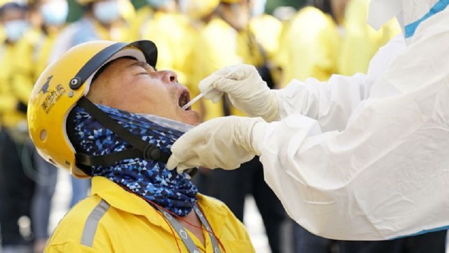 Un trabajador sanitario en un traje protector realiza una prueba de ácido nucleído para un repartidor, en Pekín, China.