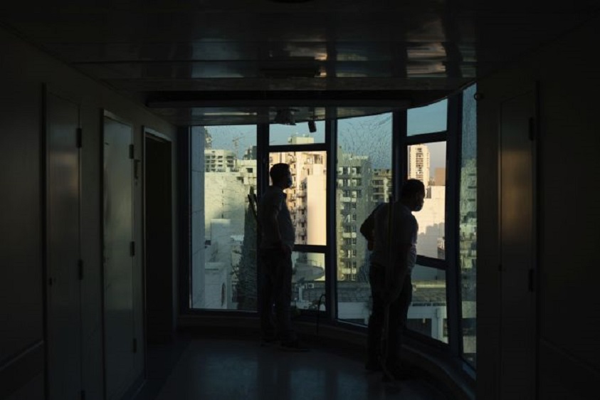Dos trabajadores miran a través de una ventana rota en el hospital de Saint George, que quedó muy dañado por la masiva explosión. (Fuente: Felipe Dana / AP)