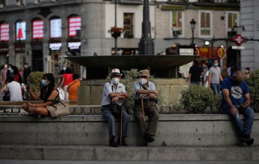 Dos hombres con mascarilla sentados en una fuente de Madrid. (Fuente: Anadolu Agency vía Getty Images)